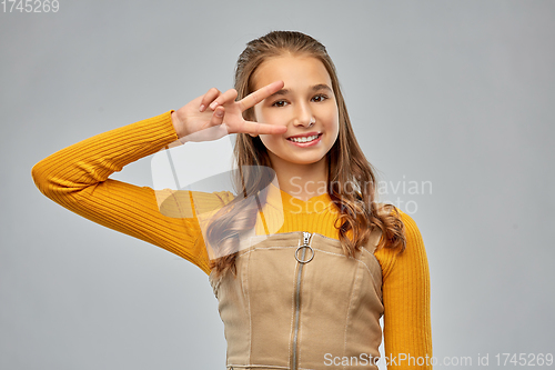 Image of smiling young teenage girl showing peace hand sign