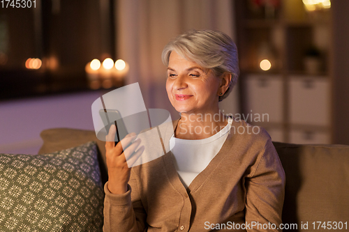 Image of happy senior woman with smartphone at home