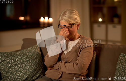 Image of tired senior woman in glasses at home at night