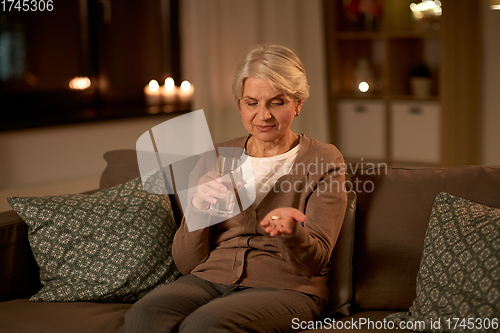 Image of senior woman with water and medicine at home