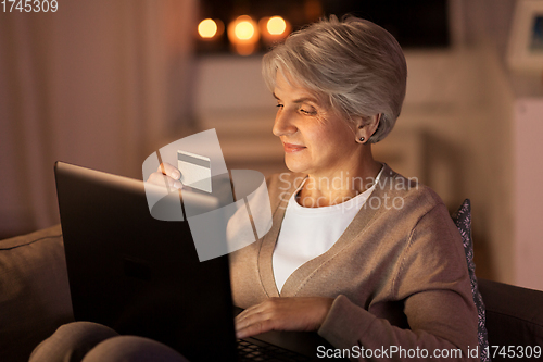 Image of senior woman with laptop and credit card at night