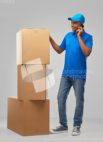 Image of indian delivery man with boxes calls on smartphone