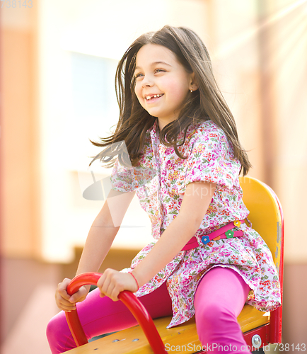 Image of Young happy girl is swinging in playground