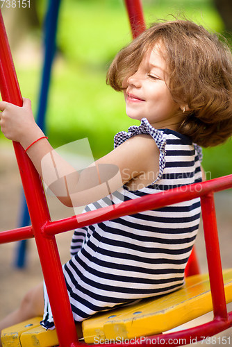 Image of Young happy girl is swinging in playground