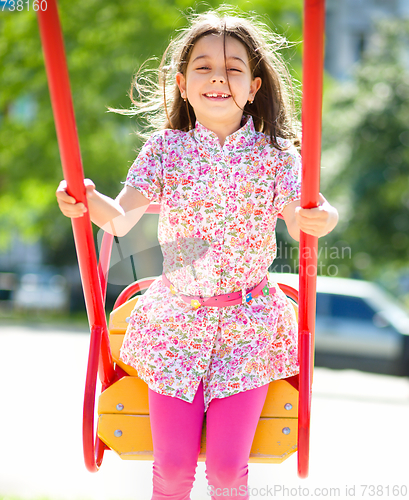 Image of Young happy girl is swinging in playground