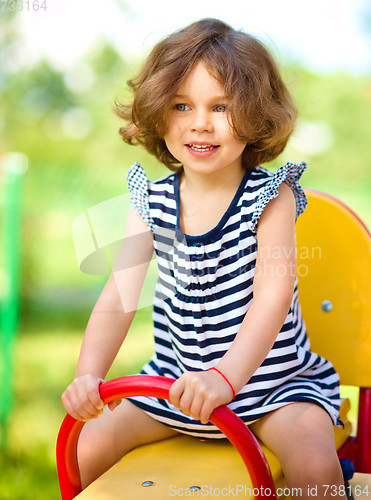 Image of Young happy girl is swinging in playground