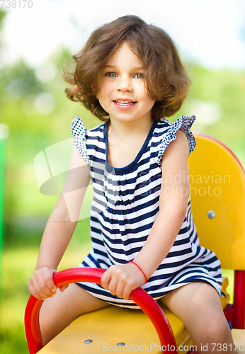 Image of Young happy girl is swinging in playground