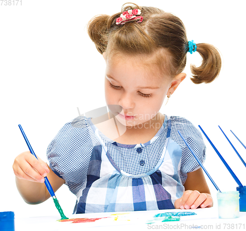 Image of Little girl is painting with gouache