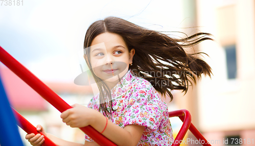 Image of Young happy girl is swinging in playground