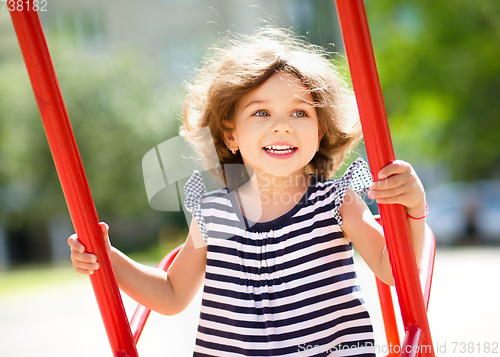 Image of Young happy girl is swinging in playground