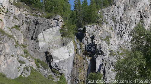 Image of Big beautiful waterfall flows down the rocks mountains