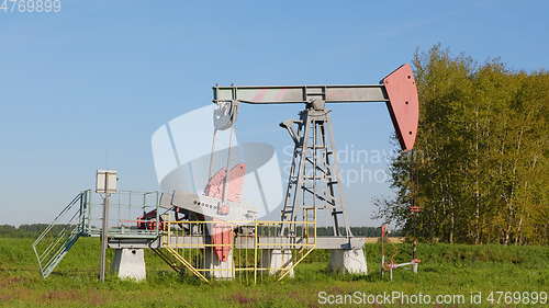 Image of Operating oil and gas well in oil field, profiled against the blue sky