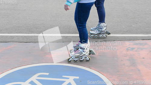 Image of Feet of two girls riding on a roller skates ride on asphalt.