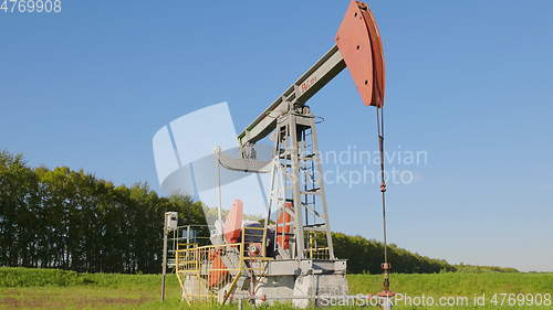 Image of Operating oil and gas well in oil field, profiled against the blue sky