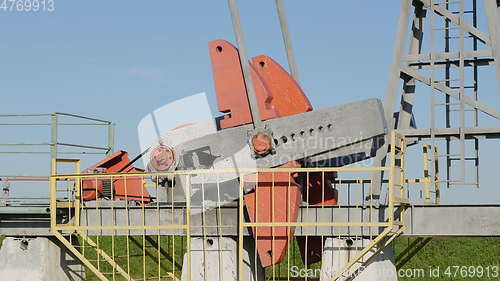 Image of Operating oil and gas well in oil field, profiled against the blue sky