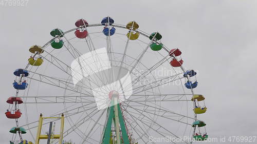 Image of Underside view of a ferris wheel over blue sky.