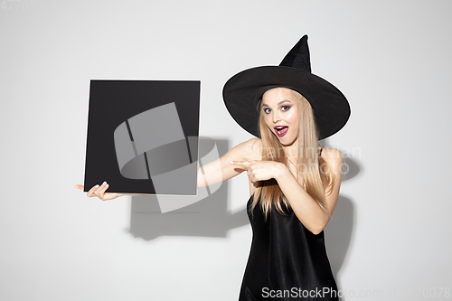 Image of Young woman in hat as a witch on white background