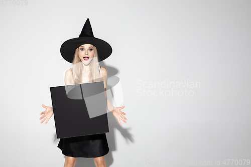 Image of Young woman in hat as a witch on white background