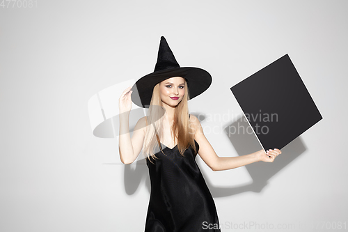 Image of Young woman in hat as a witch on white background