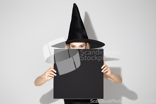 Image of Young woman in hat as a witch on white background