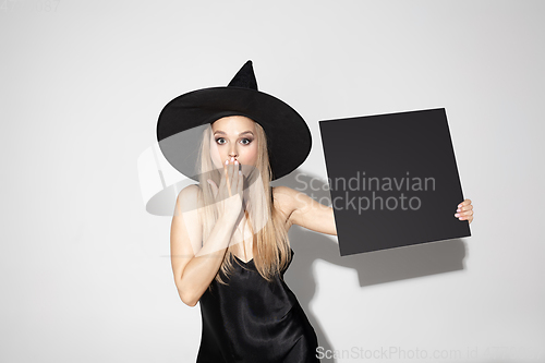 Image of Young woman in hat as a witch on white background