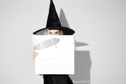 Image of Young woman in hat as a witch on white background