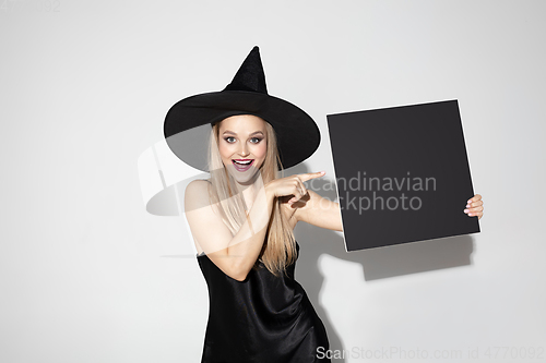 Image of Young woman in hat as a witch on white background