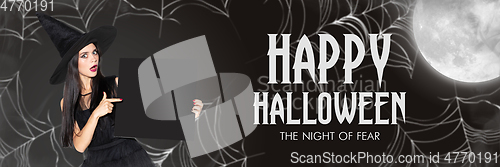 Image of Young woman in hat as a witch on scary black background