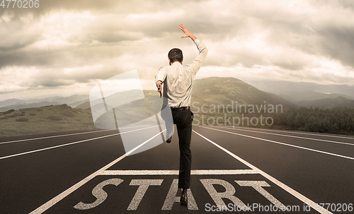 Image of Businessman jumping on a starting grid with cityscape on the background