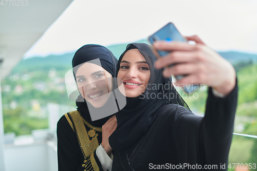 Image of Portrait of young muslim women taking selfie on the balcony