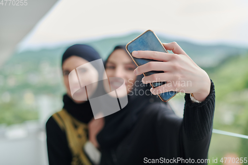 Image of Portrait of young muslim women taking selfie on the balcony