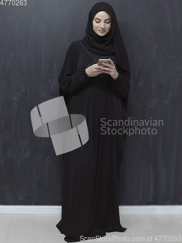 Image of Young muslim businesswoman in traditional clothes or abaya using smartphone