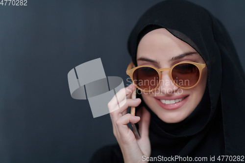 Image of Young muslim businesswoman in traditional clothes or abaya using smartphone