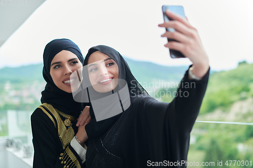 Image of Portrait of young muslim women taking selfie on the balcony