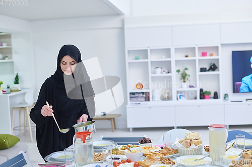 Image of Young muslim woman serving food for iftar during Ramadan