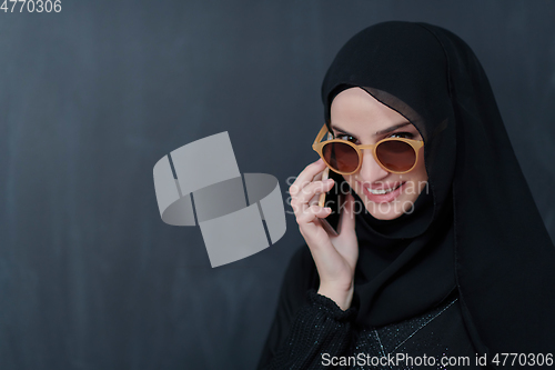 Image of Young muslim businesswoman in traditional clothes or abaya using smartphone