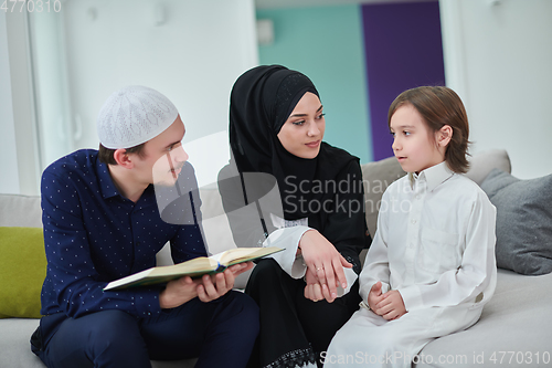 Image of Young muslim family reading Quran during Ramadan