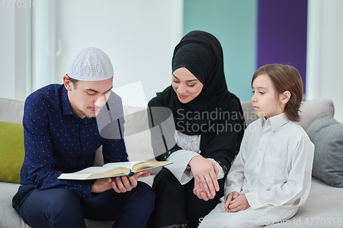 Image of Young muslim family reading Quran during Ramadan