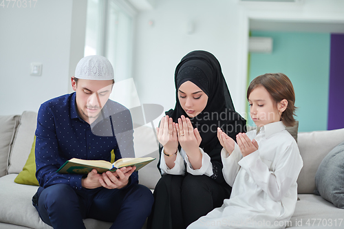 Image of Young muslim family reading Quran during Ramadan