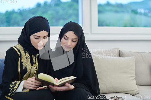 Image of Portrait of young muslim women reading Quran in modern home.