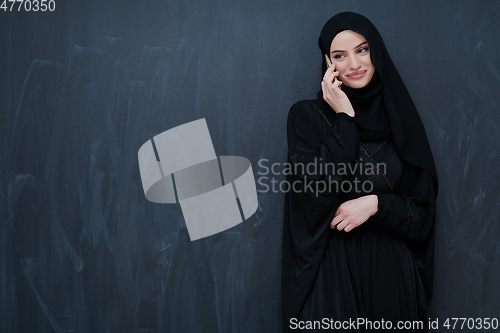 Image of Young muslim businesswoman in traditional clothes or abaya using smartphone