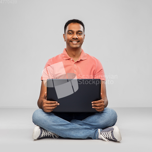Image of happy indian man with laptop computer on floor