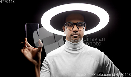 Image of man in glasses with smartphone under illumination