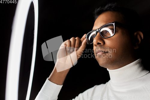 Image of man in glasses under white illumination over black