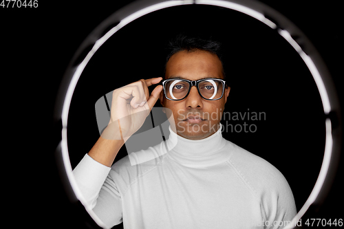 Image of man in glasses over white illumination on black