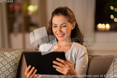 Image of happy woman with tablet pc at home in evening