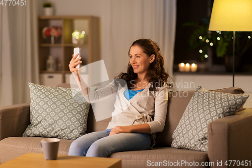 Image of happy woman taking selfie with smartphone at home