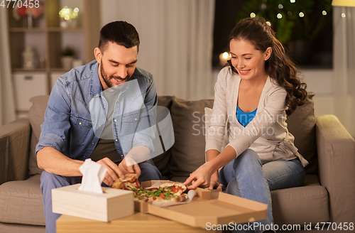 Image of happy couple eating takeaway pizza at home