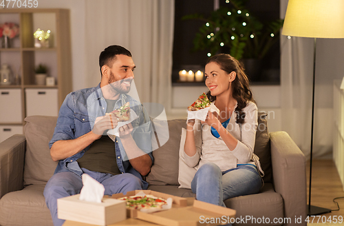 Image of happy couple eating takeaway pizza at home