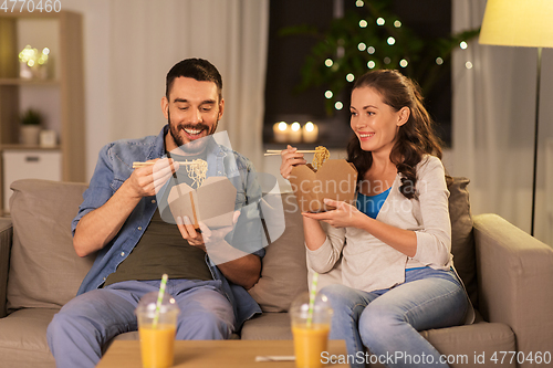 Image of happy couple eating takeaway noodles at home